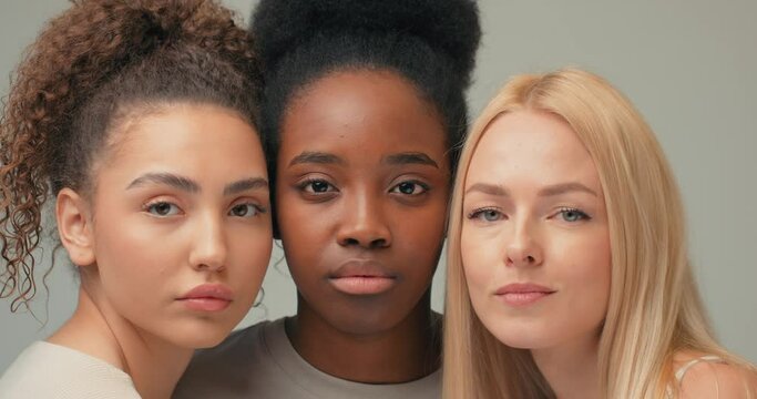 gorgeous three Caucasian African Hispanuc women looking at camera blinking closing opening eyes Slow motion Natural beauty skin health care. Spa, wellness concept. white beige background Cyclogram.