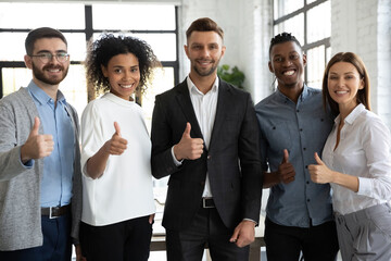 Group portrait of smiling young multiracial businesspeople look at camera show thumb up give recommendation, happy motivated multiethnic diverse colleagues recommend good company service or deal
