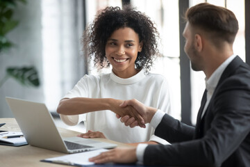 Smiling multiethnic business partners shake hands get acquainted greeting at office meeting, happy...