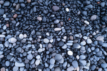 Fototapeta na wymiar Gray pebbles as a background. Round stones on the beach. Photography for design. Image for background and wallpaper. Textures in nature.