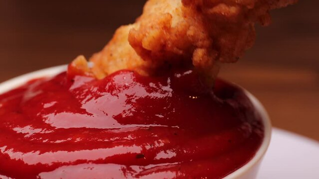 nuggets dip in ketchup, rotation in circle. fraud filet chicken nuggets Turning. selective focus	