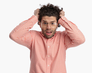 irritated young man with glasses screaming while pulling curly hair