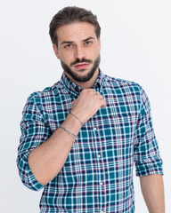 Fototapeta premium confident young man fixing casual plaid shirt and looking forward