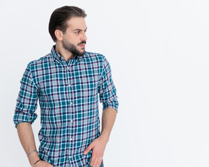 Fototapeta premium young casual man in plaid shirt holding hands in pockets and looking to side