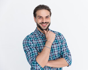 Obraz premium happy young man in plaid shirt folding arms and touching chin