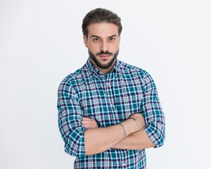 confident casual man with beard in plaid shirt crossing arms