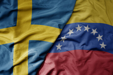 big waving national colorful flag of sweden and national flag of venezuela .