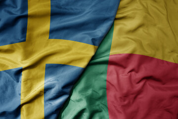 big waving national colorful flag of sweden and national flag of benin .