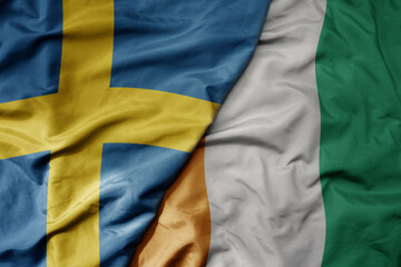 big waving national colorful flag of sweden and national flag of cote divoire .