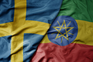 big waving national colorful flag of sweden and national flag of ethiopia .