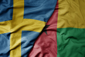 big waving national colorful flag of sweden and national flag of guinea bissau .