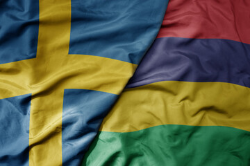 big waving national colorful flag of sweden and national flag of mauritius .