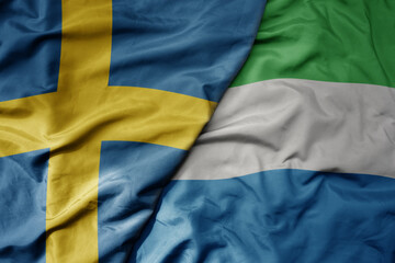 big waving national colorful flag of sweden and national flag of sierra leone .