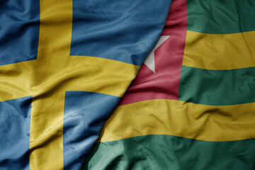 big waving national colorful flag of sweden and national flag of togo .
