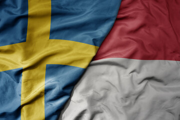 big waving national colorful flag of sweden and national flag of indonesia .