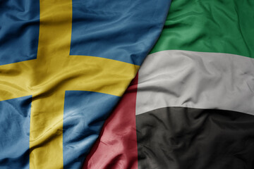 big waving national colorful flag of sweden and national flag of united arab emirates .