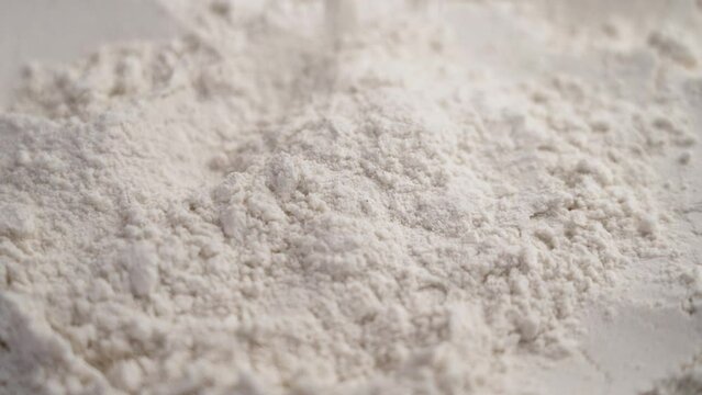 White rice flour particles falling in slow motion. Dietary gluten free bakery ingredient. Rotation