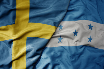 big waving national colorful flag of sweden and national flag of honduras .