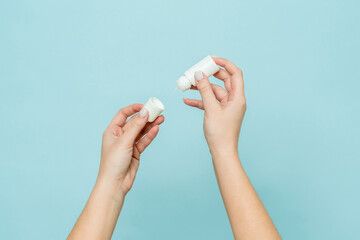 Bottle of eye drops (nasal spray) in woman's hand. Copy space