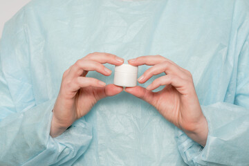 Hand of doctor holding jar of ointment, pills, tablets. Medicine bottle mockup