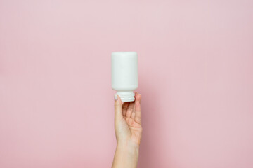 Bottle of pills or vitamins in woman's hand. Product branding mockup.