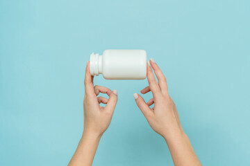 White plastic tube in female hand. Bottle for pill, capsule or supplement. Product branding mockup