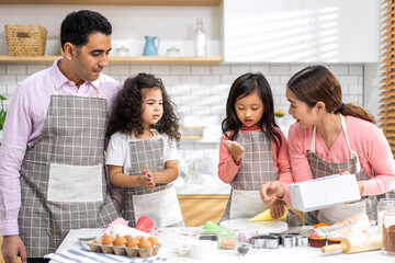 Portrait of enjoy happy love asian family father and mother with little asian girl daughter child play and having fun cooking food together with baking cookie and cake ingredient in kitchen