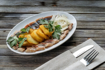 Herring with potatoes, cilantro, onions. Classic Russian dish. There's a knife and fork next to it