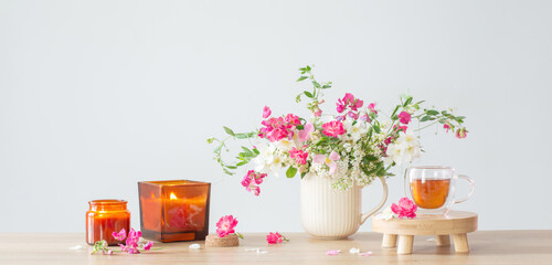 summer flowers, burning candles and cup of tea   on light background