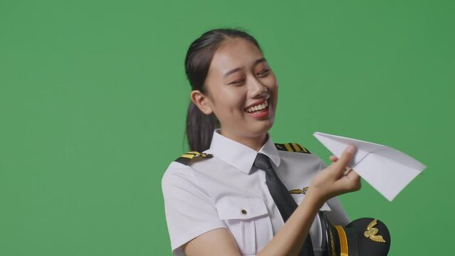 Close Up Of Asian Woman Pilot In Professional Uniform Launching Paper Plane, Holding Jet Model In Hands, Aviation Academy Aviator, Aircraft Captain On Green Screen Background Studio
