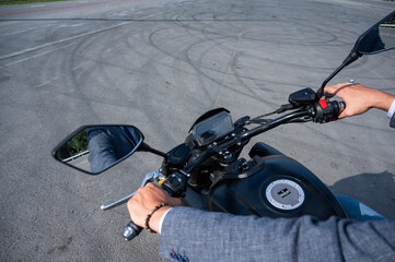 Caucasian man rides an electric motorcycle. Close-up of male hands on the steering wheel. 