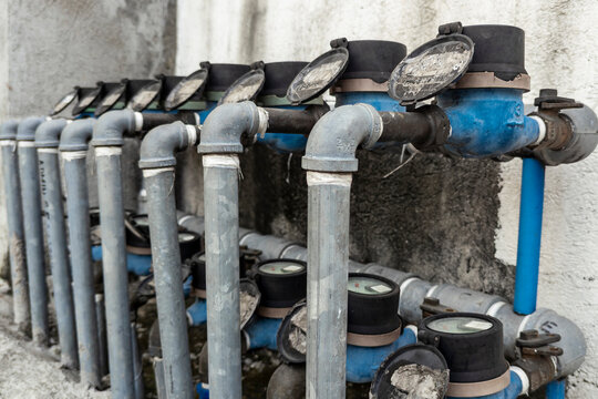 Several analog water meters installed outside an apartment building or other commercial property. Water bill and usage separated per tenant.