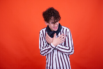 Funny curly guy posing in the studio on an orange background. Illness and protection against colds.