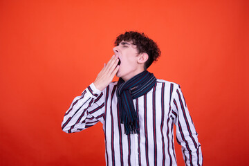 Funny curly guy posing in the studio on an orange background. Illness and protection against colds.