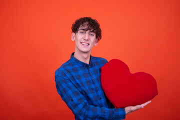 Funny curly guy posing in the studio on an orange background.