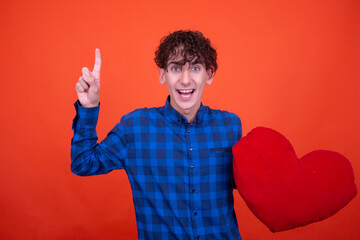 Funny curly guy posing in the studio on an orange background.