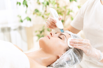 Obraz na płótnie Canvas Ultrasonic facial cleansing in professional beauty clinic for young woman