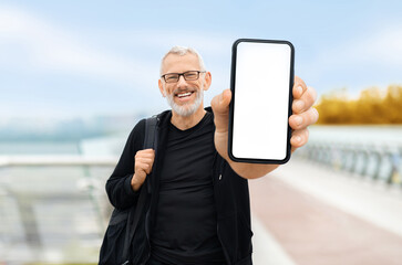 Sporty senior man showing smartphone with blank screen at camera
