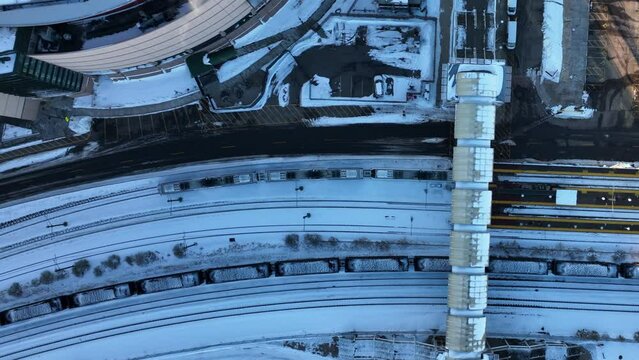 Top drone view of light rail train moving along tracks on sunny winter day