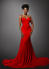 Fashion Dark Skin Woman in Red Sexy Dress. African Model with Afro Hairstyle in Long Evening Gown over Gray. Stylish Lady with Golden Earrings and Red Lip Makeup happy smiling Portrait