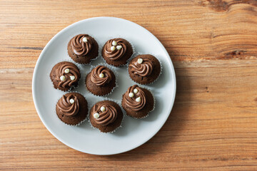 Mini chocolate cupcakes in a plate on a pine table surface