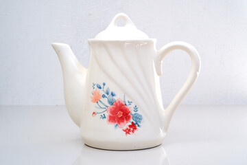 Antique ceramic teapot with floral pattern on white background