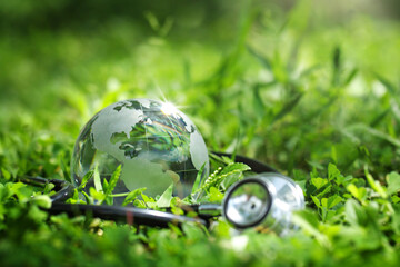 Environment Earth Day Concept.Crystal Earth with a medical doctor's stethoscope on green.Saving...