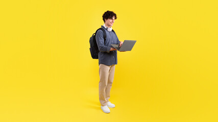 Fototapeta na wymiar Young Student Guy Using Laptop Learning Standing On Yellow Background