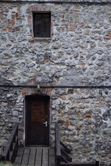 Fototapeta na wymiar Building in medieval style with an entrance through an old door. Old wooden bridge