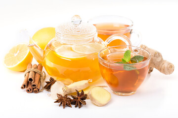 Health-preserving hot drink concept. Side view image of a cup of ginger tea, teapot, cinnamon sticks, lemon, anise and mint leaves on a white background