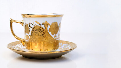 Antique porcelain coffee cup on white background with reflection. Dishes with gold pattern. Table...
