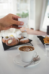 unrecognizable man pouring sugar into a cup on a white table at a coffee shop