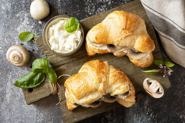 French pastry, tasty freshly baked sandwich. Vegan food style. Croissant with cream cheese and mushroom on a stone background.  View from above.