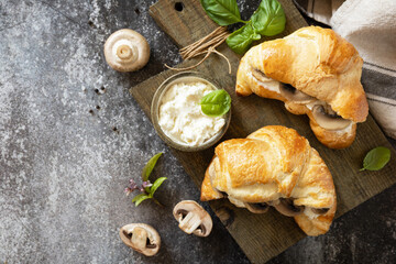 Croissant with cream cheese and mushroom on a stone background. French pastry, tasty freshly baked sandwich. Vegan food style. View from above. Copy space.